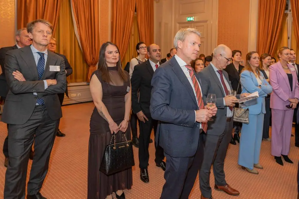 Guests standing and listening to a speech in an ornate hall