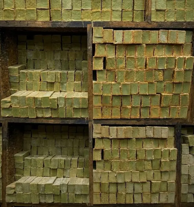Shelves of green Aleppo soap bars stacked to cure in a wooden storeroom
